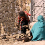 A woman with her daughter collecting dry dung cakes used for burning purpose