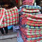 A vendor displaying quilts to attract the customers at his shop during winter season.