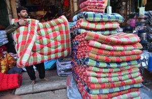 A vendor displaying quilts to attract the customers at his shop during winter season. 
