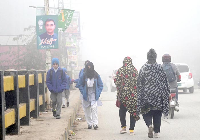 Students on the way to school at Ghouri Town during heavy fog in the morning.