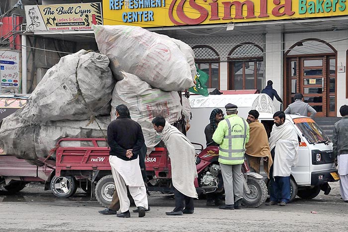 Traffic police official issuing challan to rickshaw loader driver due to overloading which is a violation of the traffic rule at Lathrar Road, Khana Pull.