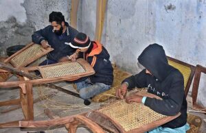 Workers busy in netting wooden chairs at their place in a local market.