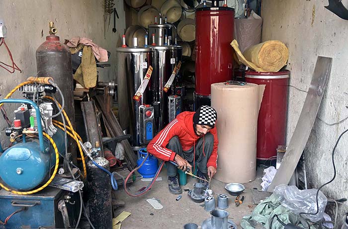 A worker busy in making gas geyser at his workplace.