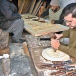 Artisans busy in carving different designs on wooden door in workshop at Saidpur Road.