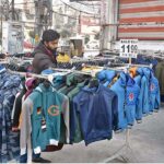 A vendor arranging and displaying warm clothes to attract the customers at Commercial Market.