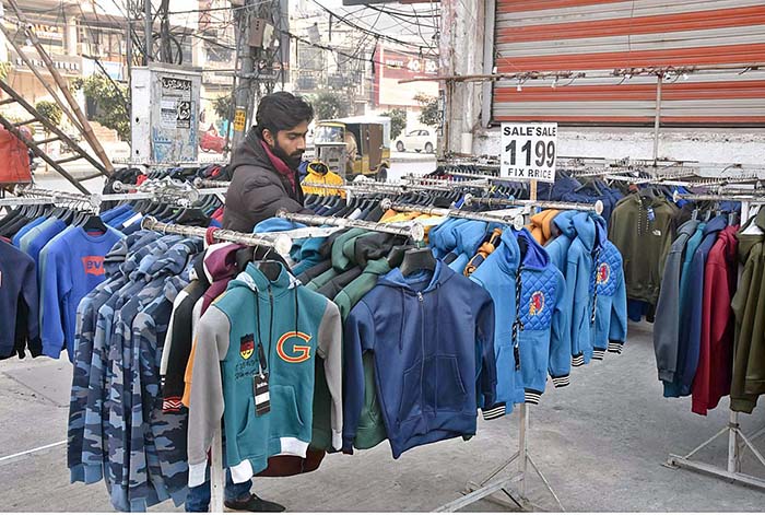 A vendor arranging and displaying warm clothes to attract the customers at Commercial Market.
