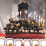 A young vendor selling charcoal-roasted sweet potatoes to attract customers at his roadside setup