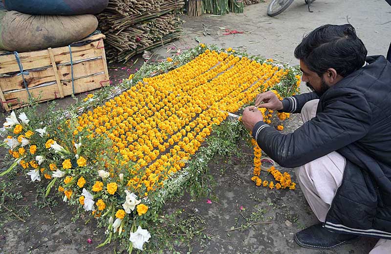 A vendor busy in preparing flower chaddar to be used in Mehndi functions at Bani Chowk