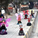 A vendor arranging and displaying dolls to attract the customers on footpath along Murree Road.