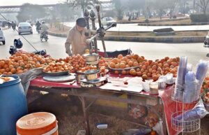 A vendor arranging and displaying oranges for extracting juice at his roadside setup in Federal Capital