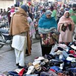 Women busy in selecting and purchasing old shoes from roadside vendor.