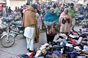 Women busy in selecting and purchasing old shoes from roadside vendor. 