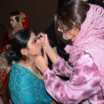 A beautician makeup a bride during mass marriage ceremony organized by Maina Foundation at The University of Faisalabad