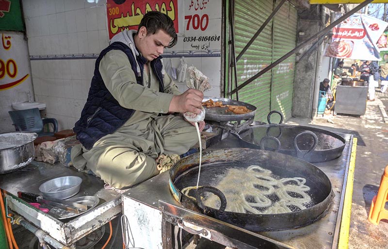 A vendor busy in preparing traditional sweet item “Jaleebi” at his workplace