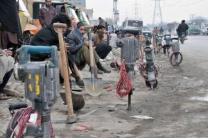 Labourers alongwith their tools sitting on roadside waiting for clients to be hired for work during morning time at KhannaPul