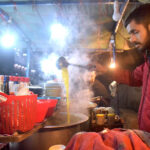 A vendor displaying Chicken Yakhni to attract the customers at his roadside setup during night.