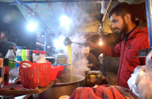 A vendor displaying Chicken Yakhni to attract the customers at his roadside setup during night. 