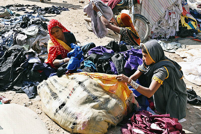 Labourer women busy in arranging and sorting old clothes at SITE area