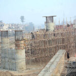 Labourers busy in construction work of flyover bridge on Jhumra Road near Abdullahpur.