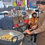 A vendor busy in roasting peanuts at his roadside setup.