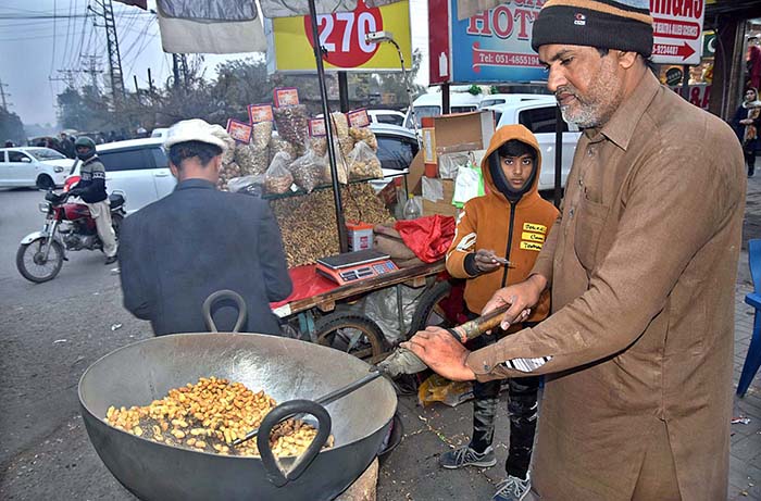 A vendor busy in roasting peanuts at his roadside setup.