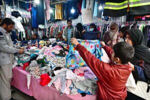 Customers selecting and purchasing old clothes displayed by the Weekly Bazaar vendors to attract the customers