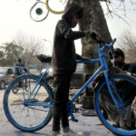 Worker repairing bicycle at his roadside workplace in the Federal Capital