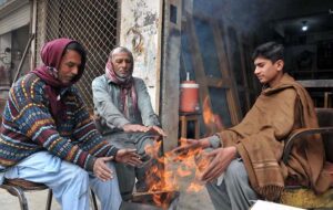 Shopkeepers sitting around fire to keep them warm during cold weather in the Federal Capital.