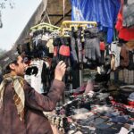 A youngster selecting and purchasing gloves from vendor at Aabpara in Federal Capital.
