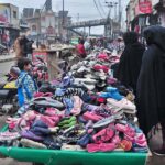 Vendors displaying old shoes to attract the customers at his roadside setup.