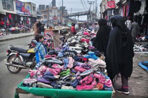  Vendors displaying old shoes to attract the customers at his roadside setup.