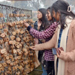 Visitors selecting keychain from a roadside vendor stall.