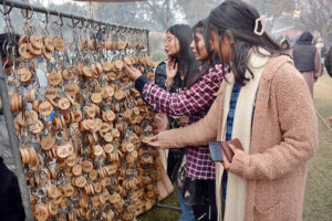 Visitors selecting keychain from a roadside vendor stall.