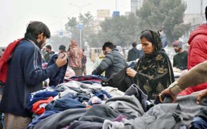 People busy in selecting and purchasing old warm clothes from roadside vendor. 