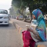 A young girl selling traditional item (Maronda) while sitting ON footpath at Club Road