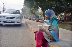 A young girl selling traditional item (Maronda) while sitting ON footpath at Club Road