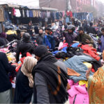People busy selecting and purchasing old warm clothes from roadside in the city
