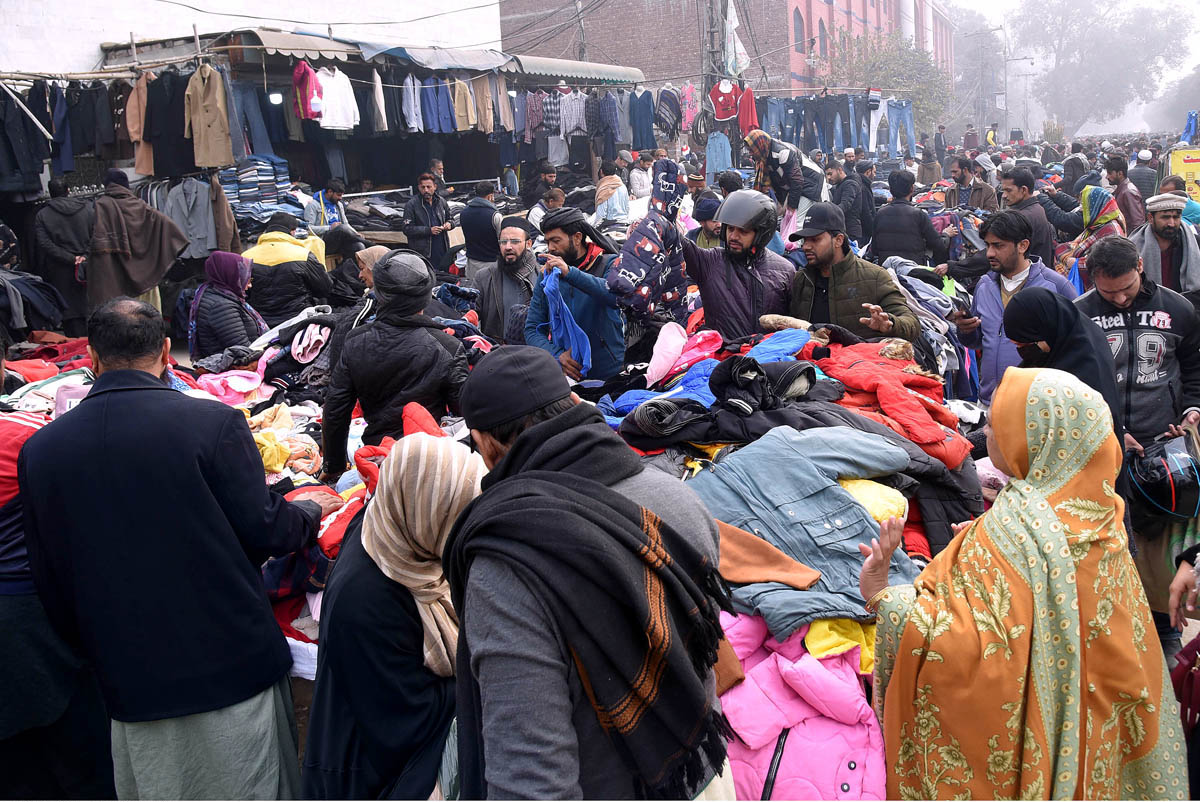 People busy selecting and purchasing old warm clothes from roadside in the city