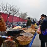 A vendor selling roasted corn to attract the customers outside Weekly Bazaar