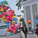 An elderly vendor selling different shapes balloons to children at Satellite Town.