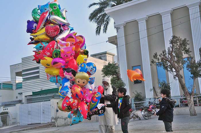 An elderly vendor selling different shapes balloons to children at Satellite Town.