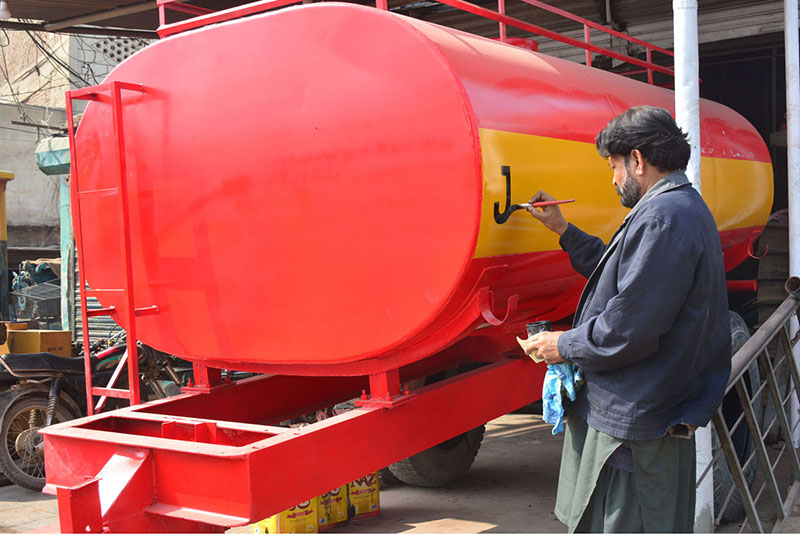 A worker busy in paint on the tanker body at his workplace