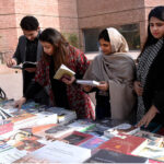 People selecting books from a Book Fair at Al-Hamra