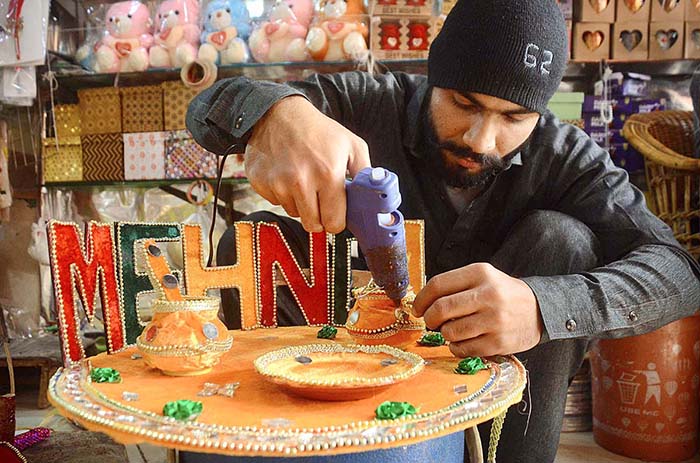 A shopkeeper is decorating various items used for mehndi functions at his shop to attract the customers at Fawara Chowk.