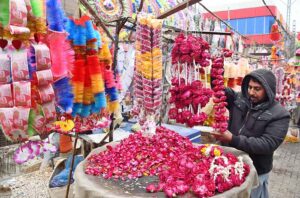 A vendor arranging flower garlands to attract the customers at his roadside setup.