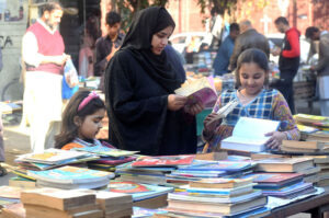 Family selecting and purchasing old books from a roadside setup at Mall Road