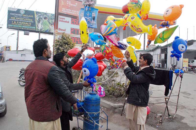 A vendor selling different shapes balloons to customers at roadside vendor