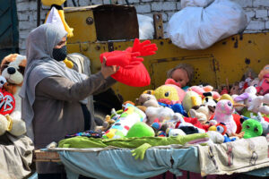 A woman selecting and purchasing cloth toys from vendor stall outside road