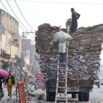 Labourers are busy loading old cardboard and paper on the tractor trolley