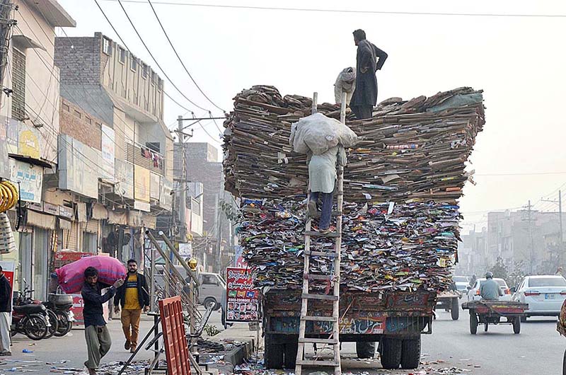 Labourers are busy loading old cardboard and paper on the tractor trolley